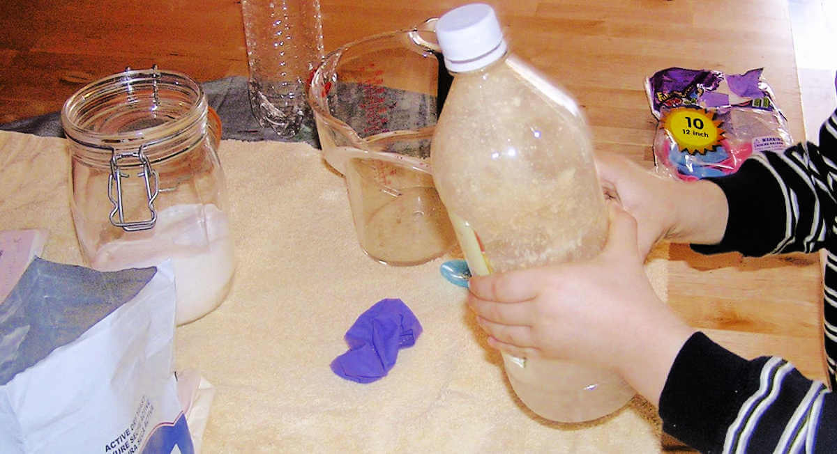 Child shaking bottle filled with water, sugar and yeast mixture