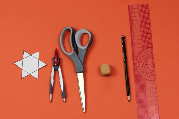 Supplies for drawing a 6 point star: scissors, compass, ruler and pencil